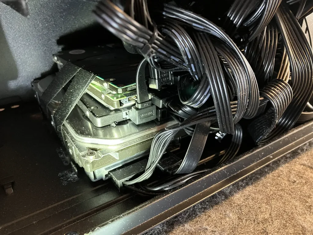 A close-up shot of several hard drives and an old SSD that were roughly bundled and held together with black insulation tape inside the Budget Gaming PC. This terrible build, showing components held together with tape, was brought into Bluesdigital because it was not working.