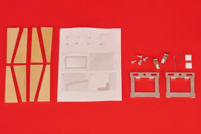 Displayed on a red background. Wall hanging kit - Instructions, stretching wedges, metal hangers, screws, pins and soft sticky pads.