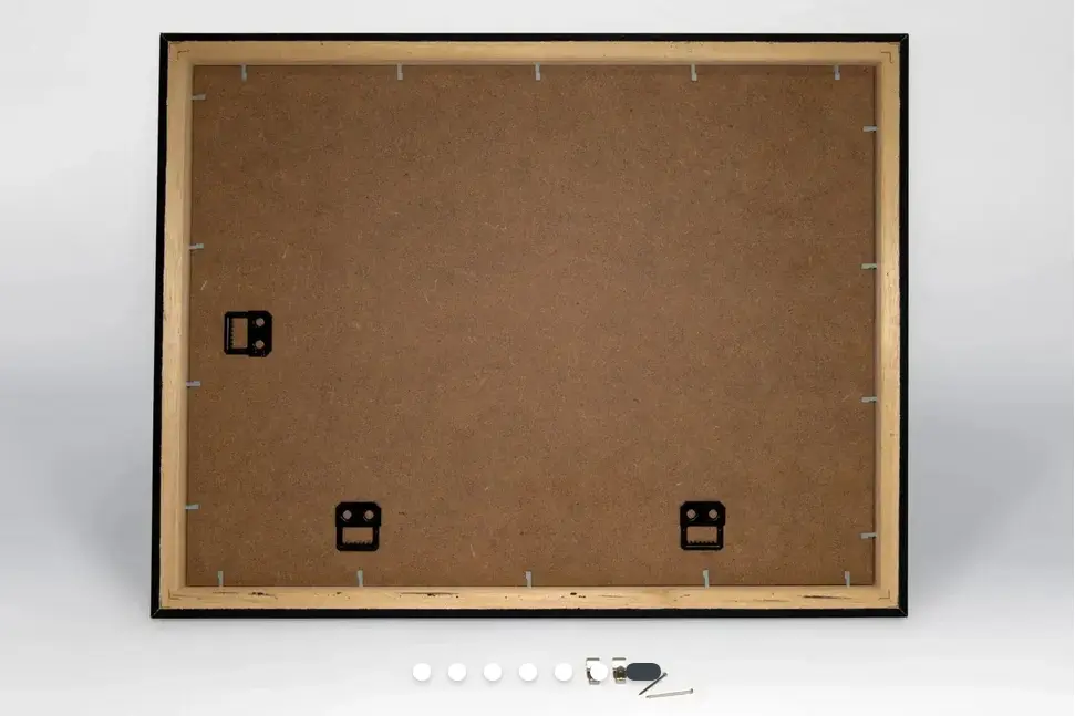 A photo showing the back of a picture frame. You can see the tabs that you bend to open it to put your prints inside, and the three holders for hanging on the wall.