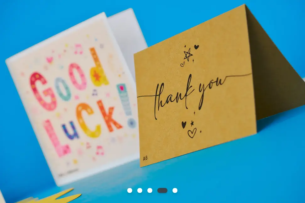 The close-up of a kraft paper printed thank you card, with a happy good luck card in soft focus behind.
