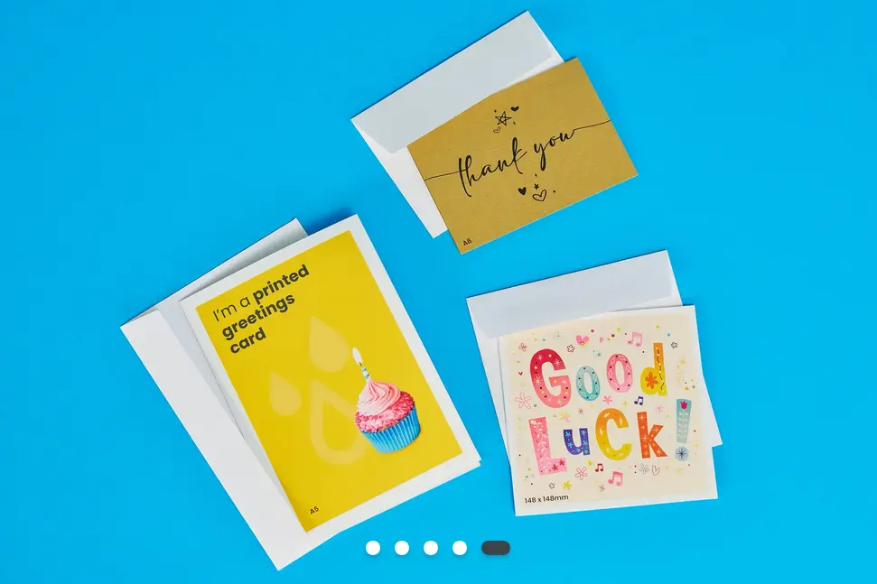 Three greetings cards against a bright blue background. One says 'Thank you'. One says 'Good Luck'. One says, ' I'm a printed greetings card'