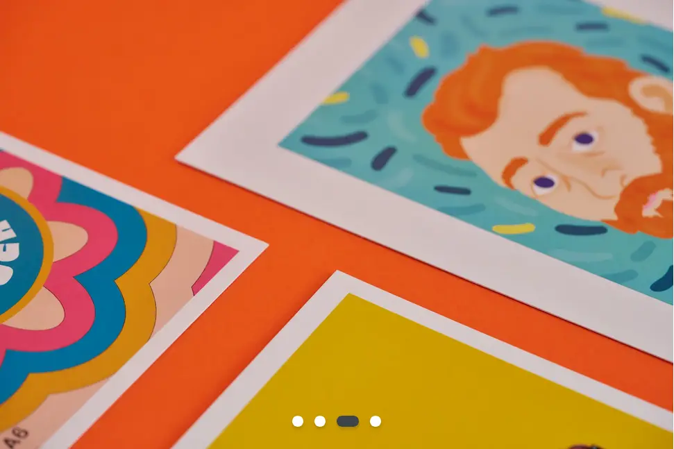 A close-up of the three corners of three different postcards - one has a drawing of a red-haired man staring with blue eyes.