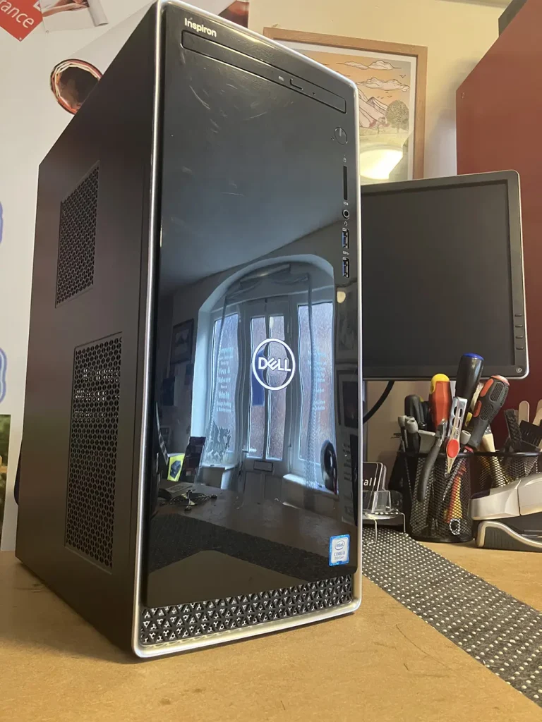 The Dell inspiron 3670 Refurbished Desktop PC sitting on the Bluesdigital Workshop Desk. You can see the shop windows reflected in the PC.